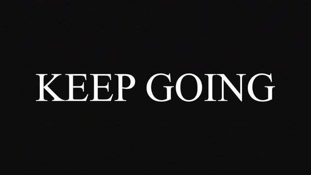 Motivational phrase 'Keep Going' repeated across dark background during cinematic presentation with subtle lighting shifts