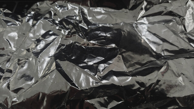 Crumpled silver aluminum foil texture background close up.