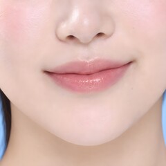 Obraz premium Close Up of Asian Woman with Soft Pink Lips and Smooth Skin on Light Blue Background