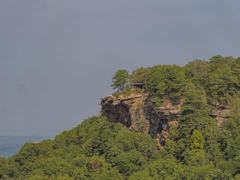 Rocky cliff with shelter and forest on mountain ridge