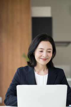 ノートパソコンで仕事をする女性会社員、オフィスで笑顔で働くビジネスウーマンのデスクワーク