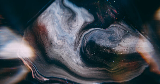 Ink spill. Sparkling fluid. Defocused purple color pigment glitter mix acrylic texture floating on abstract light art background.