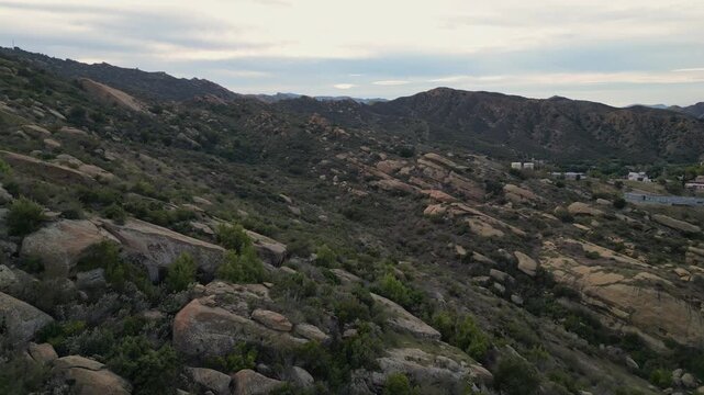 Aerial approach along the rocky Santa Susana Mountains hillside in the Santa Susana Knolls area of Simi Valley, California. Shot on an overcast afternoon, January 2024.