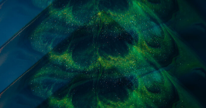 Sparkling splash. Defocused glitter ink. Green blue purple color glimmer art texture shiny fluid spilling on abstract background.