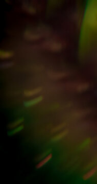 Bokeh glare. Lens flare. Defocused pink purple green multicolor radiant optical round neon texture on illuminated abstract art dark black background.