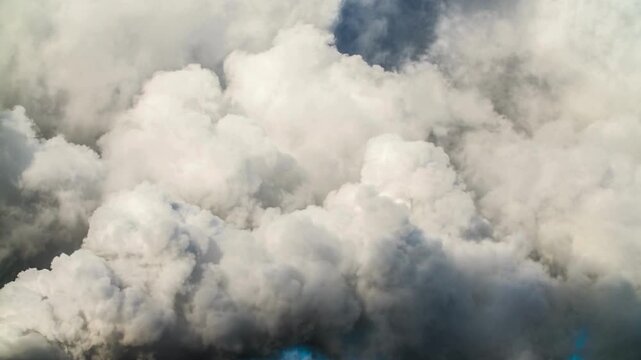 Fluffy white cumulus clouds in a bright blue sky create a hazy, soft atmosphere. Perfect for backgrounds, weather concepts, relaxation.
