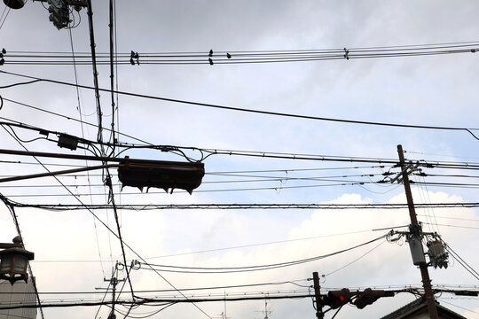 Densely webbed power lines over street lights.