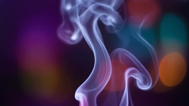 Smoke swirls rising against colorful bokeh background. Wispy blue trails of incense vapor flow gracefully in a dark studio setting. Abstract cinematic macro video footage for creative visual overlays.