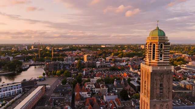 Golden-hour aerial of Zwolle, Netherlands, with the Peperbus tower beside the historic center, red-roofed streets and a canal beneath a warm evening sky.