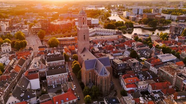 Golden-hour aerial of Zwolle, Netherlands, with the Peperbus and Basilica of Our Lady rising above dense historic streets, red rooftops and canals in warm sunset light.
