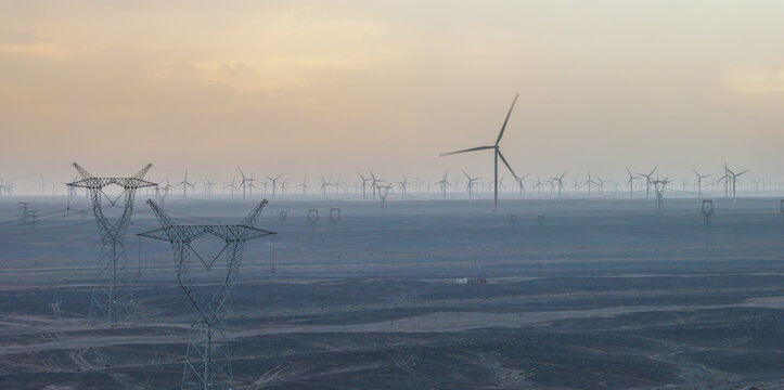 Wind Turbines and High-Voltage Transmission Towers in Desert Gobi at Dusk