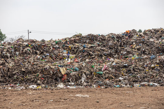 Large heap of unsorted solid household waste and plastic refuse at an outdoor dumping site, pollution concept.