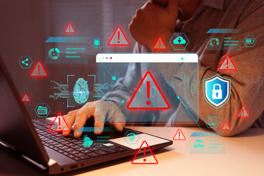 Hand typing on laptop with glowing red warning symbols floating