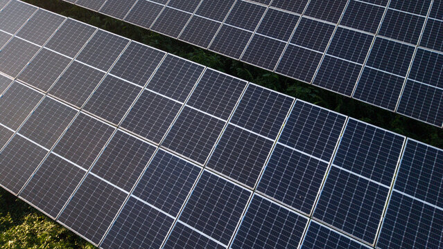 Aerial view of a large solar farm with rows of photovoltaic panels capturing sunlight for renewable energy production in a rural landscape