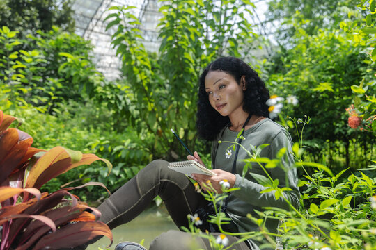 Woman with Notebook Enjoying Nature Inside a Lush Botanical Dome