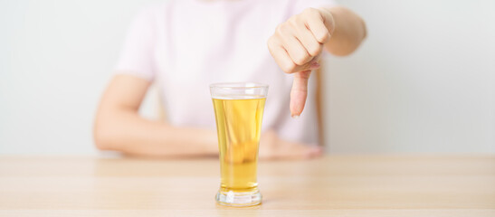 woman show thumb down hand gesture to refuse a glass of Beer, Healthy man say no to alcohol drink, stop alcoholism and addiction concept. Responsible man reject a drink before driving and quit booze © Jo Panuwat D