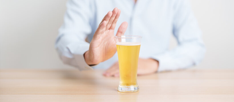 man making stop hand gesture to refuse a glass of Beer, Healthy man say no to alcohol drink, stop alcoholism and addiction concept. Responsible man reject a drink before driving and quit booze