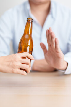 man making stop hand gesture to refuse a bottle of Beer, Healthy man say no to alcohol drink, stop alcoholism and addiction concept. Responsible man reject a drink before driving and quit booze