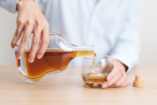 man pour cognac into a glass on table, suffering from alcohol addiction, alcoholism concept. depicting emotional distress, depression, substance abuse problem, unhealthy lifestyle and mental health
