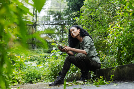 Woman with Notebook Enjoying Nature Inside a Lush Botanical Dome