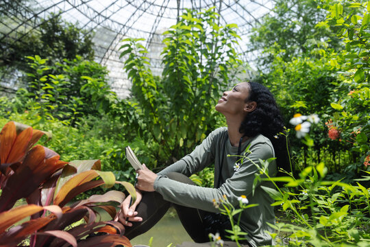 Woman with Notebook Enjoying Nature Inside a Lush Botanical Dome