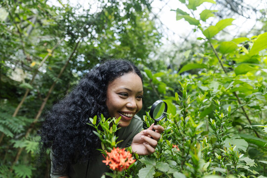 Smiling Woman Exploring Tropical Plants with a Magnifying Glass