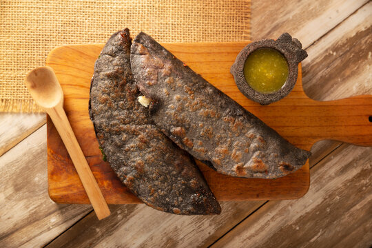 Mexican quesadillas made with blue corn tortillas filled with melted cheese and mushrooms served on a wooden cutting board.