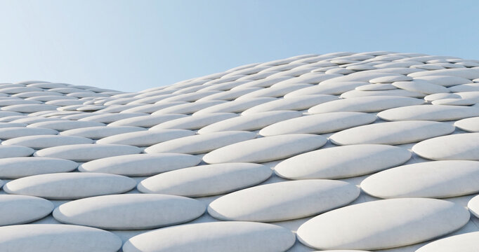 An artistic view of a modern building exterior featuring a wavy structure adorned with circular patterns against a clear blue sky.