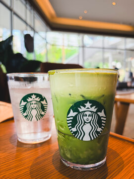 Bangkok, Thailand - September 14, 2026: Close up of a Starbucks iced matcha green tea latte and a cup of iced water on a wooden table in a brightly lit cafe.