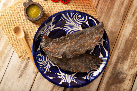 Mexican quesadillas made with blue corn tortillas filled with melted cheese and mushrooms served on a traditional plate