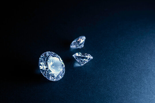 brilliant cut diamond held by tweezers on black background