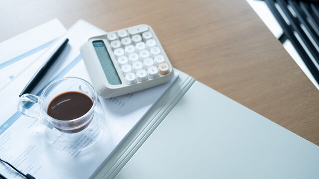 Financial workspace with coffee, calculator, pen and business reports on desk. Accounting, investment analysis, budget planning and finance management concept.