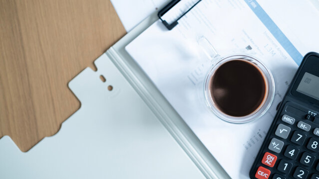 Top view of coffee and calculator on financial reports with copy space. Business accounting, budget calculation, investment analysis and financial planning concept.