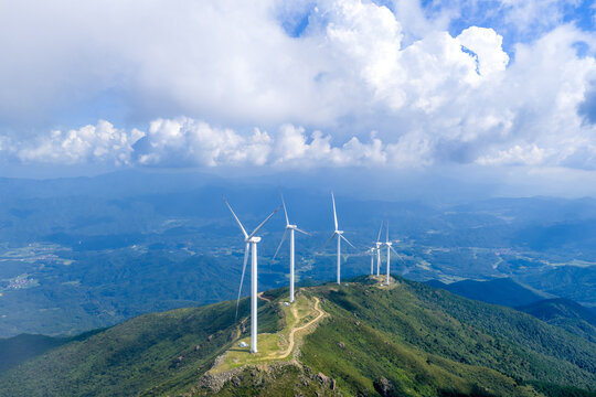 white wind turbines standing on green mountain peak under blue sky