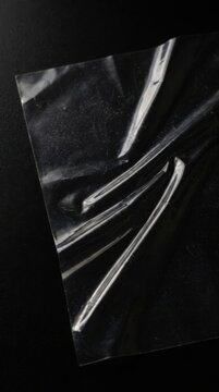 Abstract transparent acetate sheet with folds on a dark black background