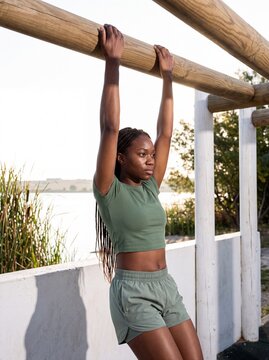 Frau trainiert am Reck im Outdoor-Fitnesspark am See