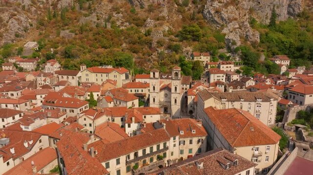 Historic Cathedral of Saint Tryphon stands among dense terracotta rooftops below a rocky hillside in Kotor&rsquo;s medieval old town.