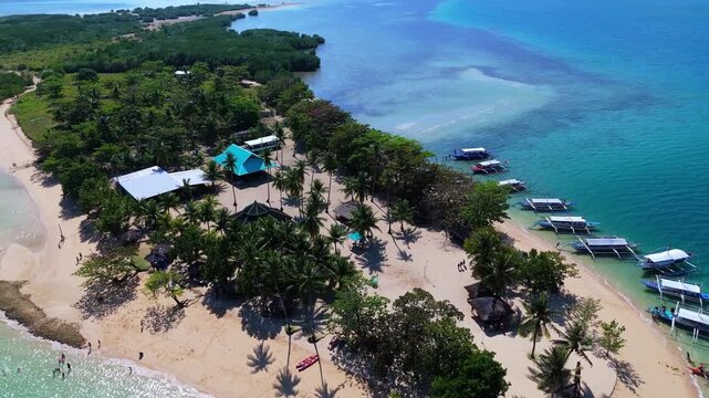 Aerial view of Cowrie Island in Honda Bay near Puerto Princesa, Palawan, Philippines, featuring a white sandy beach, lush tropical vegetation and clear turquoise water