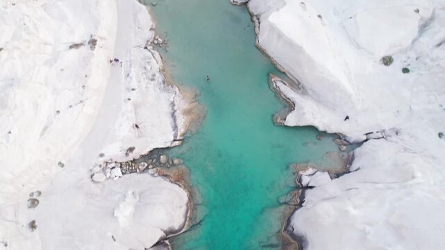 Top-down drone footage of Sarakiniko&rsquo;s white volcanic rocks and vibrant turquoise sea channel, Milos, Greece. Beautiful, contrasting natural patterns