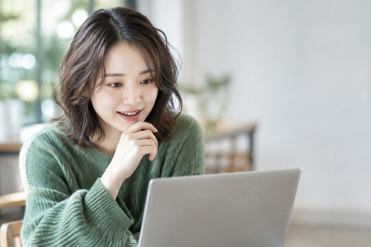 ノートパソコンを見て納得する笑顔の日本人女性