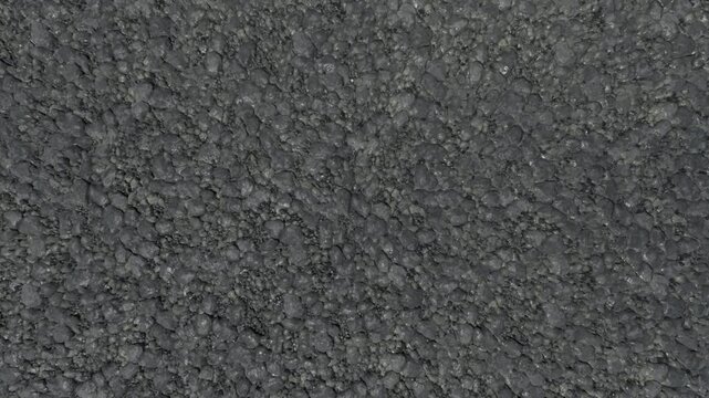 Close-up texture of dark grey asphalt with small pebbles
