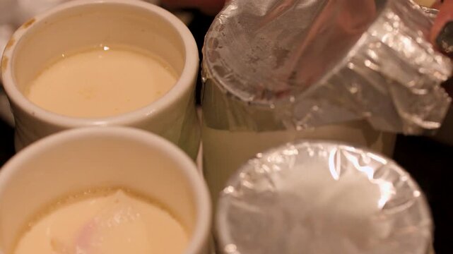 Uncovering Steamed Chawanmushi Egg Custard in Ceramic Cups at Restaurant