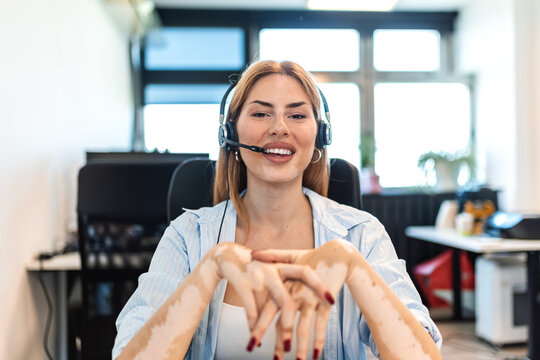 Smiling customer service representative wearing headset and talking with client. Young female telemarketer working in modern office environment. Professional communication and support concept.