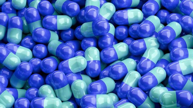 Close-up view of blue and green capsules. They are tightly packed together. Vibrant colors attract attention. Ideal for health topics. Good for science or wellness contexts. Useful in medical articles