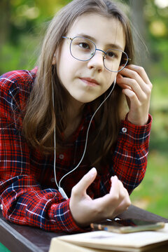 Girl in Plaid Shirt Listening to Music Outdoors with Earphones