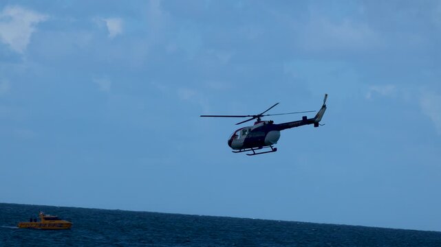Police Helicopter Flying Over Ocean Water During Maritime Patrol