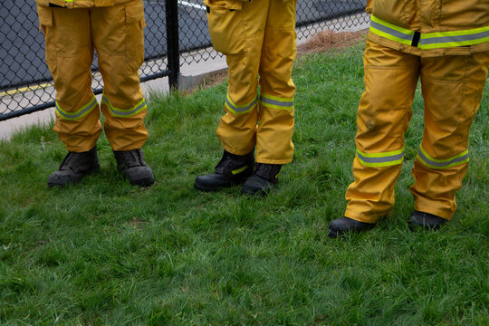legs and boots of firefighters wearing yellow protective uniforms