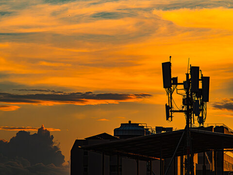 Silhouette of Cell Tower Antenna Array Against Dramatic Orange Sunset