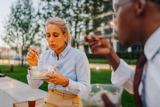 Business colleagues eating healthy lunch outdoors in park