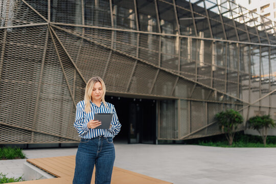 Businesswoman using tablet standing outside modern office building